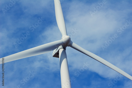 Close upward view of a giant wind power turbine propeller with a blue sky background