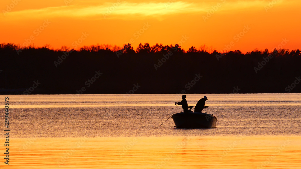 Silhouette of father and son fishing on a beautiful lake at sunset in ...