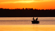 Silhouette Of Father And Son Fishing On A Beautiful Lake At Sunset In Northern Minnesota.