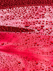 hood of red car, covered in raindrops