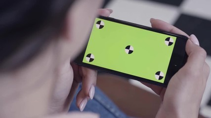 Poster - Chroma key screen for placement of your own content. Stock footage. Close-up of young woman sitting on the chair and looking at the phone with chroma key green screen.