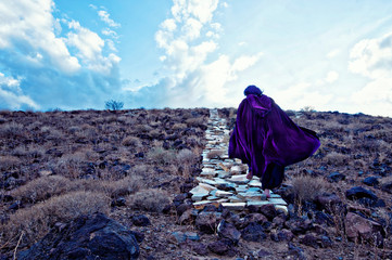 Following the Magick into the clouds. Earth and Sky surreal stone path magical journey. Traveler in purple cloak ascending the pathway into the clouds.