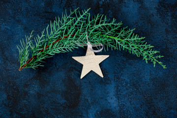 Canvas Print - A Christmas background with a white star, an ornament, and a fir tree branch, overhead shot on a dark blue background with copyspace