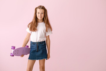 Stylish little girl with skateboard on color background