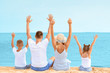 © Pixel-Shot - Happy family sitting on sea beach