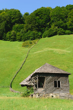 Old Abandoned Wooden House With Green Grass Hills In The Background