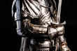 cropped view of knight in armor holding sword isolated on black