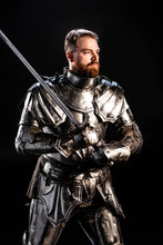 Handsome Knight In Armor Holding Sword Isolated On Black