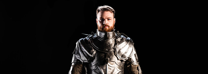 panoramic shot of handsome knight in armor isolated on black