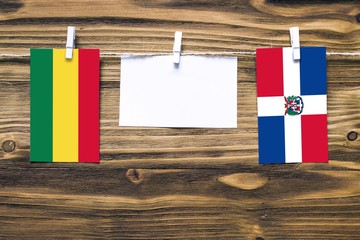 Hanging flags of Bolivia and Dominican Republic attached to rope with clothes pins with copy space on white note paper on wooden background.Diplomatic relations between countries.