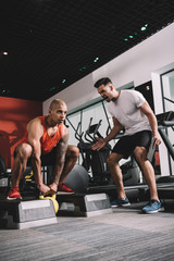 Wall Mural - excited trainer shouting while motivating african american sportsman lifting weight