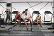 © LIGHTFIELD STUDIOS - handsome trainer looking at camera while doing lunges exercise together with multicultural athletes