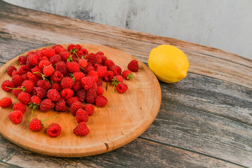 Wall Mural - Raspberries with lemon on a wooden background. Wooden blocks with the words Vitamin C, fresh fruits in the background, healthy food or diet concept. View from above. A place to write.