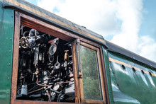 Close-up View Of The Driving Compartment Of A Large, Restored British Steam Locomotive Showing The Various Gauges And Brass Pipework Inside.