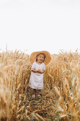 pretty cute baby girl with a beautiful smile wearing summer straw hat in a walk in the  wheat fields. selective focus. family, people concept