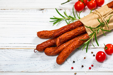 Kabanos or Cabanossi Thin Dry Smoked Polish Sausage on White Wooden Background. Selective focus.