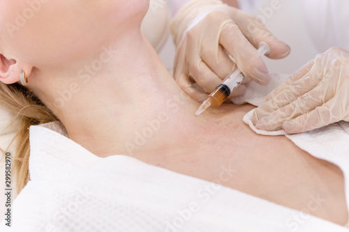Close-up of a cosmetologist\'s hand doing injections for plasma restoration and necklift to a young woman client of a cosmetology cabinet. Concept of a young neck and anti-aging skin treatments