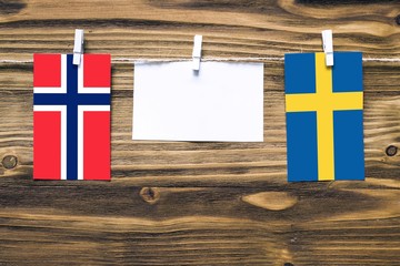 Wall Mural - Hanging flags of Bouvet Islands and Sweden attached to rope with clothes pins with copy space on white note paper on wooden background.Diplomatic relations between countries.