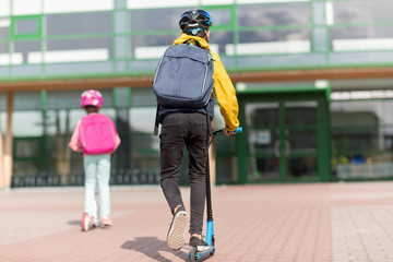 Sticker - education, childhood and people concept - happy school children with backpacks riding scooters outdoors