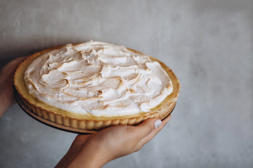 Poster - Tasty lemon meringue pie. Traditional french sweet pastry tart. Delicious, appetizing, homemade dessert with lemon cream. Copy space on female hands