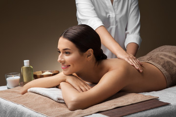 wellness, beauty and relaxation concept - beautiful young woman lying and having back massage at spa