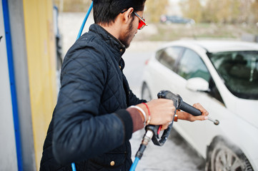 South asian man or indian male washing his white transportation on car wash.