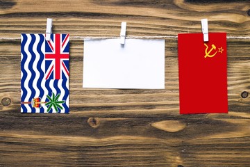 Wall Mural - Hanging flags of British Indian Ocean Territory and Soviet Union attached to rope with clothes pins with copy space on white note paper on wooden background.