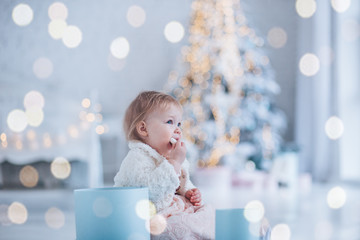 little girl eats a cookie by the New Year tree