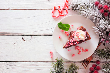 Poster - Christmas holiday candy cane chocolate cheesecake. Above view side border over a white wood background with copy space