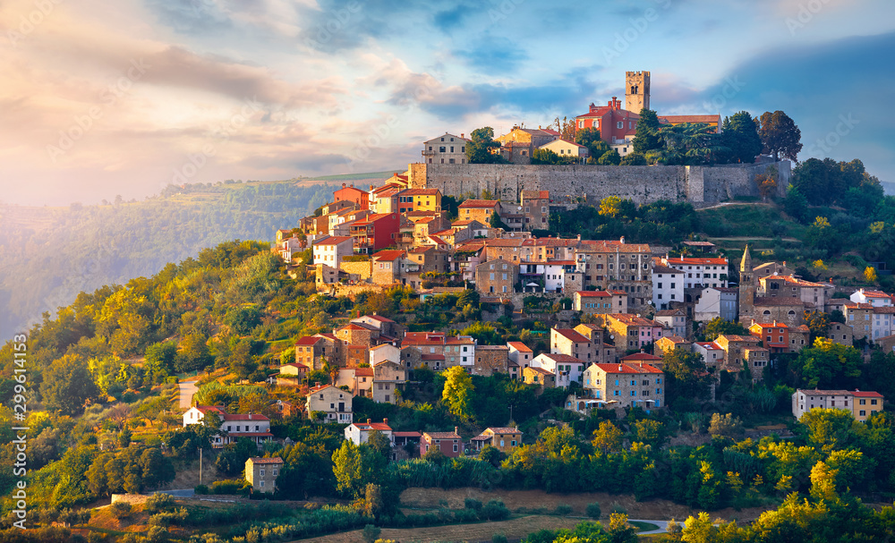 Antique city Motovun Croatia Istria. Picturesque panorama age-old village at hill with pink cloud and sunny light and authentic home with red tegular roof and green vineyard garden. - obrazy, fototapety, plakaty 