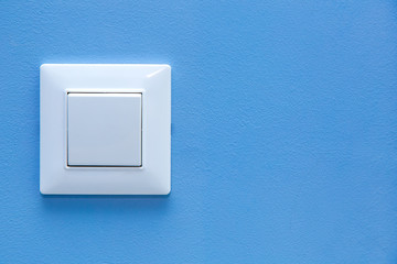 Wall Mural - a light switch, a plastic mechanical button of white color installed on a light blue wall with copy space.