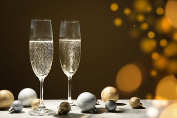 Baubles and champagne glasses on decorated background. Bokeh effect