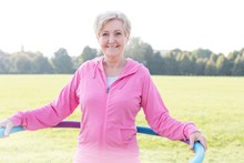Senior Woman Exercising With Hula Hoop In Park
