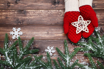 Sticker - Hands in knitted mittens holding star and fir tree branches on wooden table