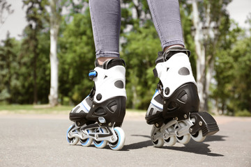 Poster - Woman with modern inline roller skates in city park, closeup