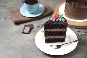 Piece of delicious chocolate cake decorated with fresh berries on grey table