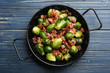 Tasty roasted Brussels sprouts with bacon on blue wooden table, top view