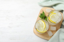 Glasses Of Cocktail With Vodka, Ice And Lemon On White Wooden Table, Top View. Space For Text