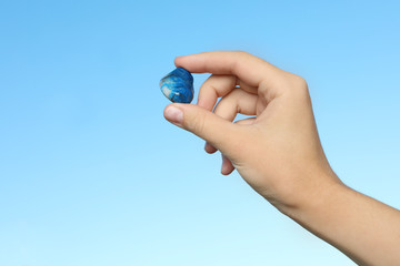 Wall Mural - Woman holding shattuckite gemstone against blue background, closeup