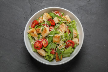 Delicious fresh Caesar salad on black table, top view