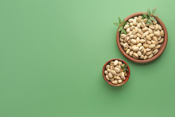 Wall Mural - Plates with tasty pistachio nuts on color background