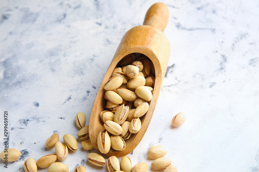 Scoop with tasty pistachio nuts on white background