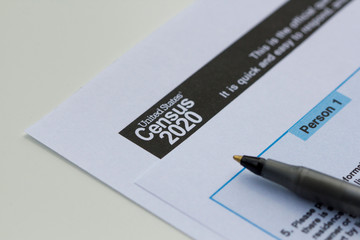 United States Census 2020 form informational copy and a ballpoint pen on a white background