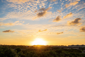 Seaside with sand dunes and colorful sky at sunset.