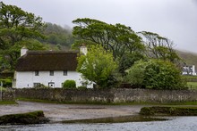 White Cottage In A Valley At Ogmore Castle In South Wales On A Cloudy Day
