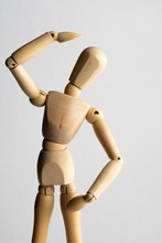 Closeup Shot Of A Wooden Pose Doll With One Hand Over Its Head And The Other On Its Waist