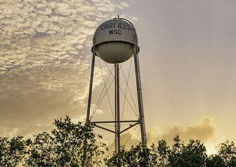 Water tower in the middle of the trees under the sunset