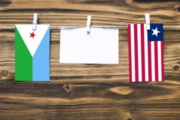 Wall Mural - Hanging flags of Djibouti and Liberia attached to rope with clothes pins with copy space on white note paper on wooden background.Diplomatic relations between countries.