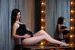 © Yarkovoy - A young pregnant woman in a black bodysuit sits near a beautiful wooden mirror with lamps. Interior Loft.