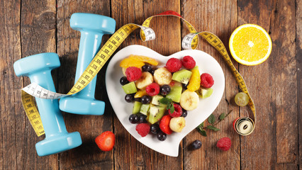 Wall Mural - fruit salad with dumbbell and meter, fitness concept